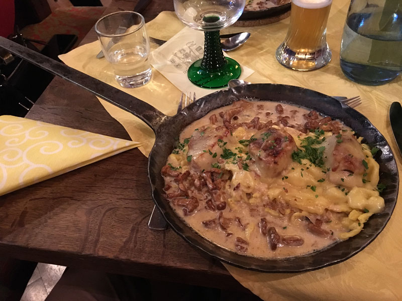 a skillet of pork medallions, mushrooms and spaetzle in a rich cream sauce